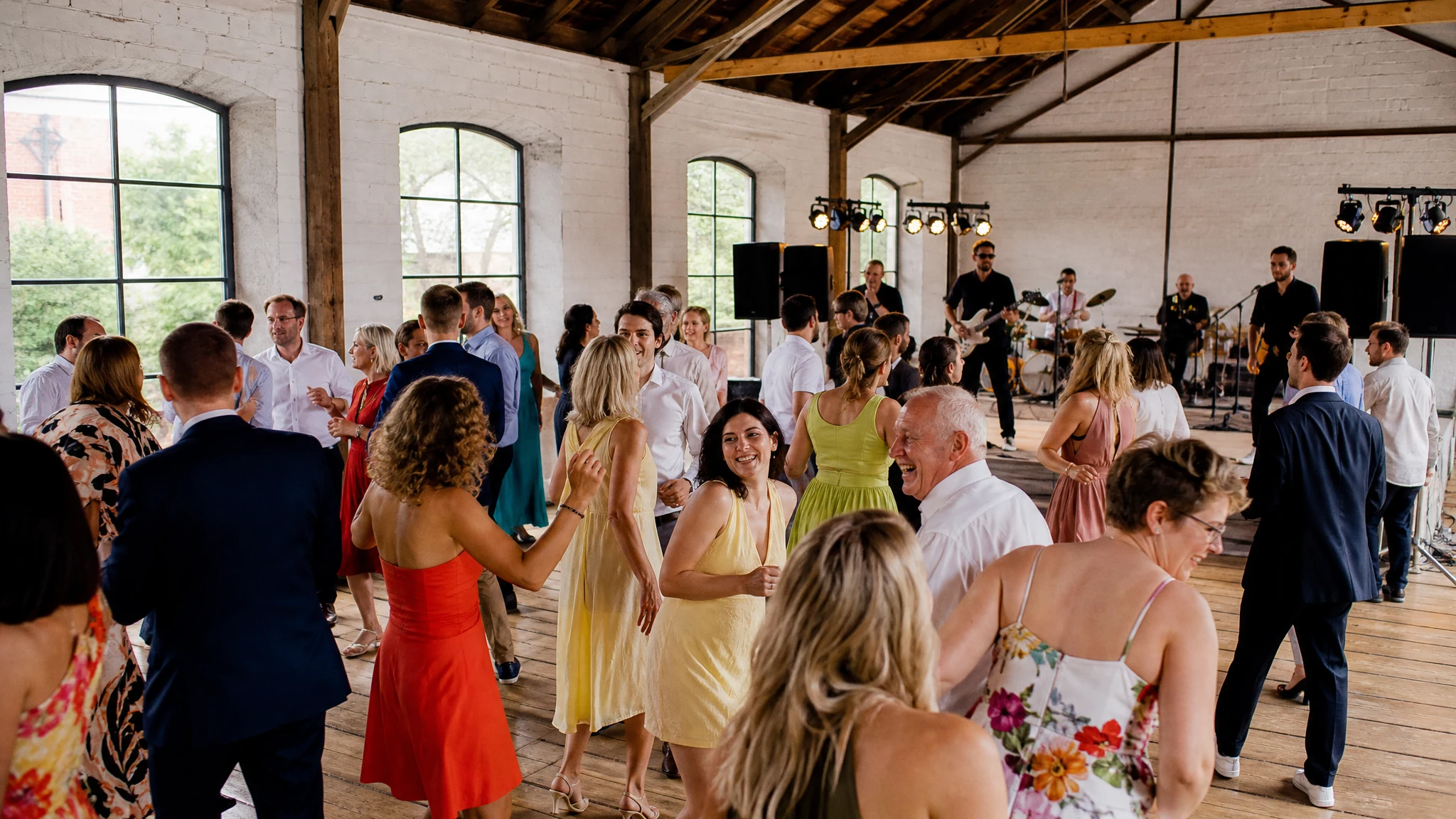 Gäste tanzen vor einer Band in einer hellen Halle, die als Hochzeitslocation in der Nähe von Köln dient