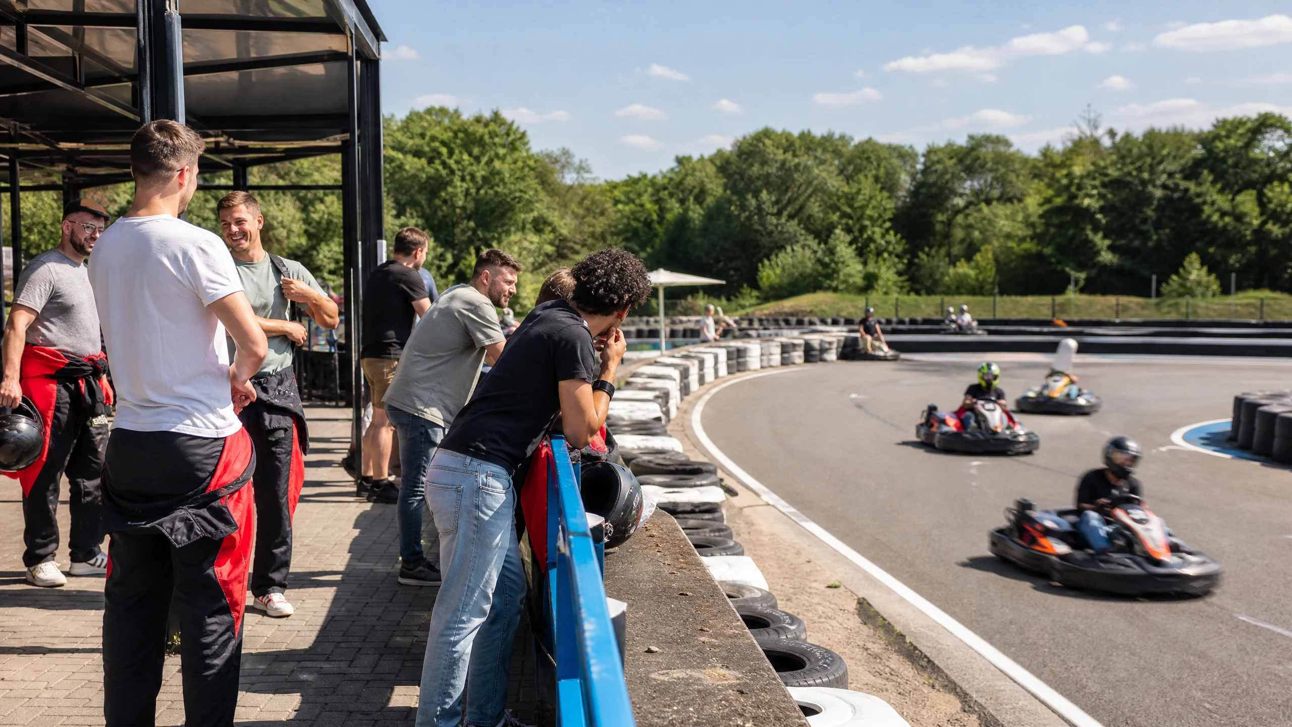 Eine Gruppe Männer schaut an einer Kartbahn zu, die sich als Location für einen Junggesellenabschied eignet