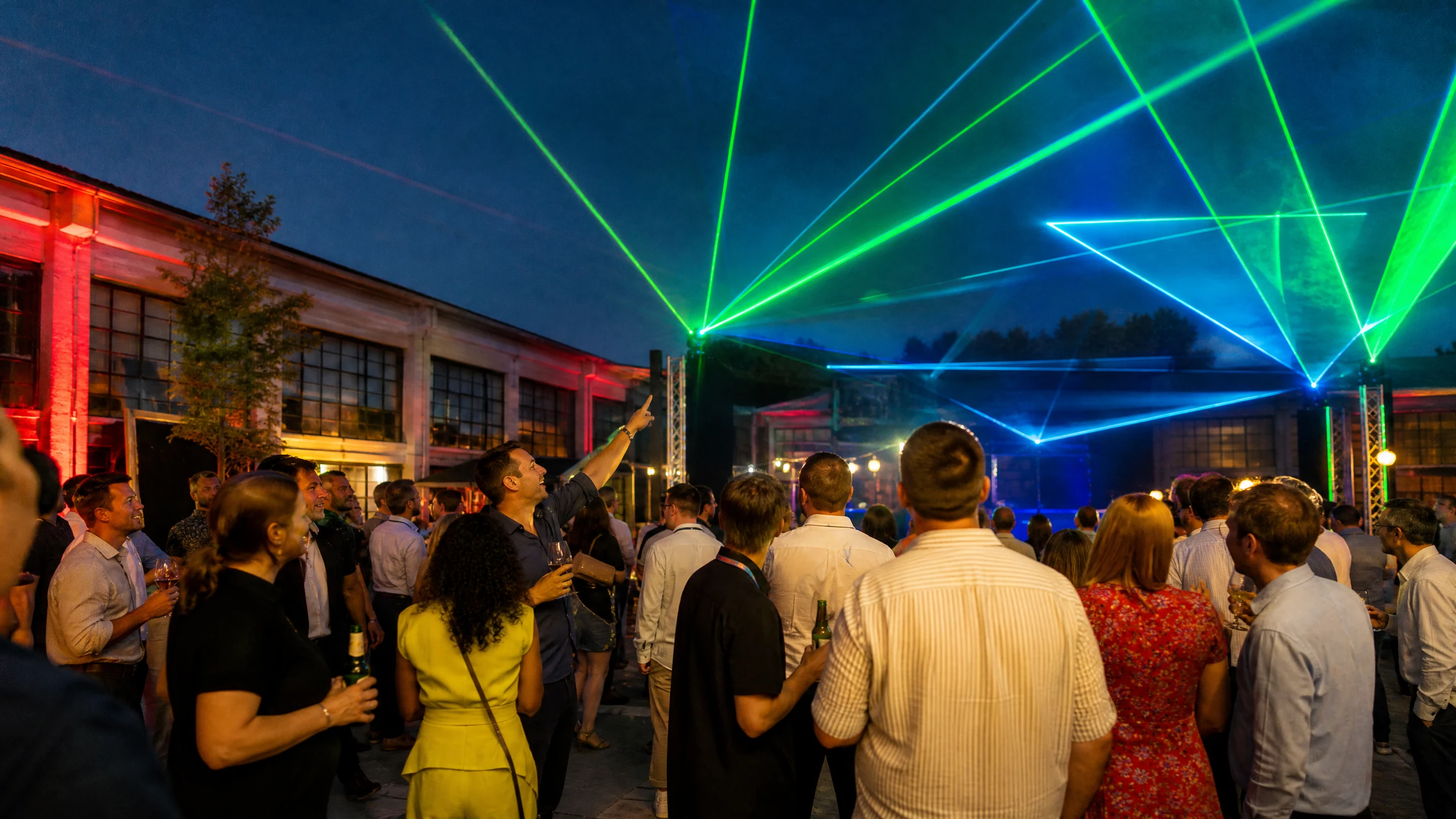 Gäste schauen abends auf einem Hof zu grünen und blauen Strahlen einer gebuchten Lasershow in Buchen